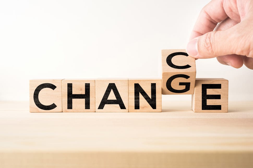 Das Wort "Change", geschrieben aus hölzernen Buchstabenwürfeln, wobei eine Hand das "g" zum "c" dreht, so dass das Wort "Chance" entsteht
